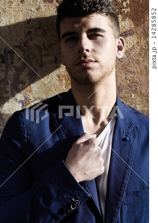 Handsome young man with blue eyes posing near a wall Handsome young man with blue eyes posing near a wall 14285852