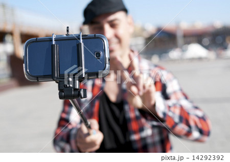 young man taking a selfie with a monopod young man taking a selfie with a monopod 14292392