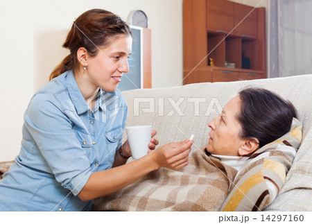 Adult daughter giving pills to mature woman 14297160