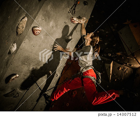 Young woman practicing rock-climbing on a rock wall indoors Young woman practicing rock-climbing on a rock wall indoors 14307512