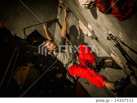 Young woman practicing rock-climbing on a rock wall indoors 14307513