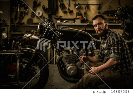 Mechanic building vintage style cafe-racer motorcycle in custom garage Mechanic building vintage style cafe-racer motorcycle in custom garage 14307533
