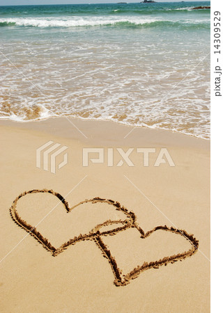 couple drawing a heart on wet golden beach sand 14309529