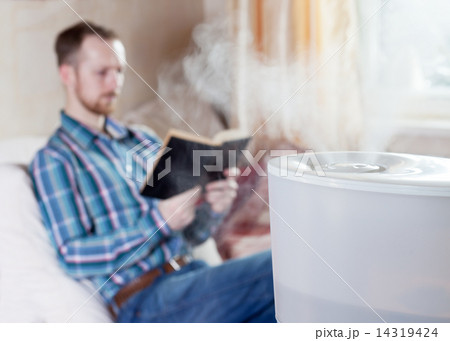 Man reading book on the background of humidifier Man reading book on the background of humidifier 14319424