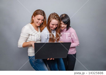 Three girls girlfriends, looking laptop laugh on a gray backgrou 14325606