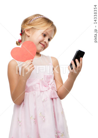 Little girl with red paper heart looking at the phone Little girl with red paper heart looking at the phone 14338354