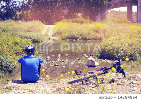 cyclist getting some rest at the riverside with a retro filter e 14394964