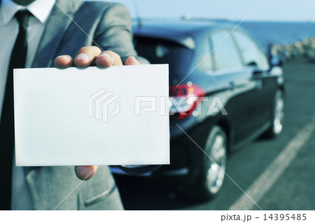 man in suit holding a blank signboard with a car in the backgrou man in suit holding a blank signboard with a car in the backgrou 14395485