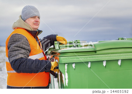 Worker near the garbage containers in winter 14403192