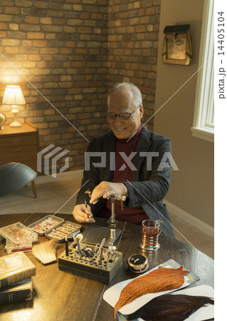 フライフィッシングの道具を作るシニア男性 14405104