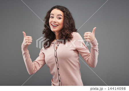 Young woman smiling and showing thumbs up 14414098