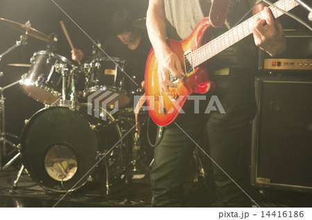 地下ライブ会場で演奏するロック系バンドのライブ ギターとドラム の写真素材