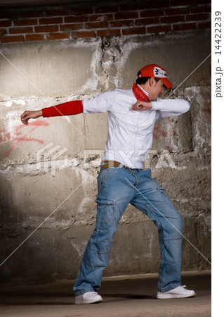 Hip hop boy dancing in modern style over grey brick wall 14422239