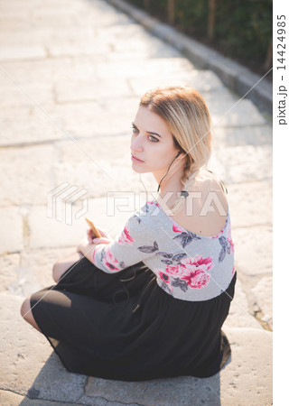 young beautiful blonde woman outdoor listening music 14424985