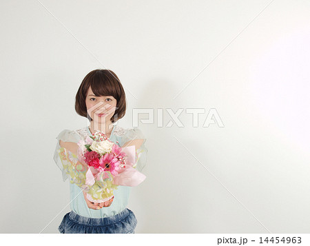 花を差し出す若い女性 14454963