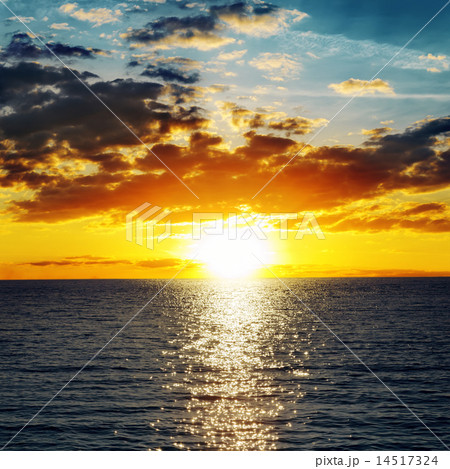 orange sunset over darken water 14517324