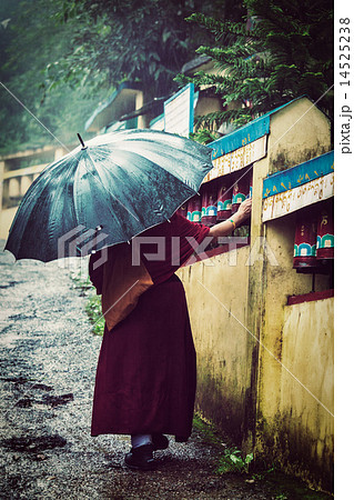 Buddhist monk with umbrella spinning prayer wheels Buddhist monk with umbrella spinning prayer wheels 14525238