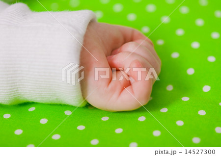 Hand of a little baby sleeping on a green cushion 14527300