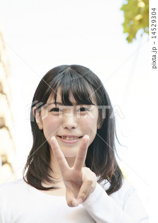 ピースサインする可愛い笑顔の女性の写真素材