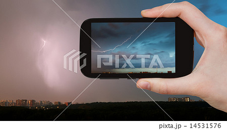 tourist photographs of lightning bolt over city 14531576