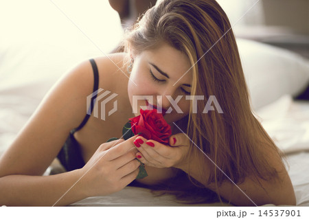 toned portrait of sexy woman posing with red rose in bed 14537901