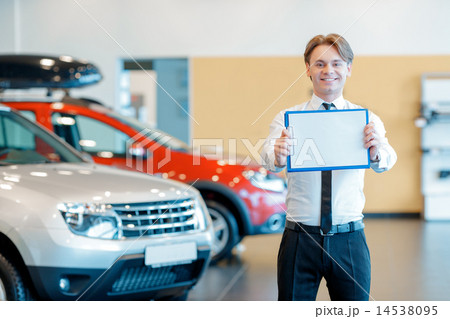 Young smiling salesman with clipboard in car dealership Young smiling salesman with clipboard in car dealership 14538095