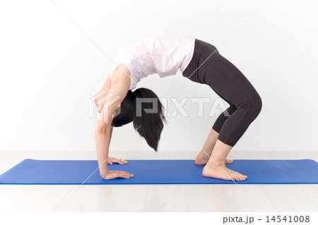 Athletic women arch into a pose while practicing yoga - SuperStock