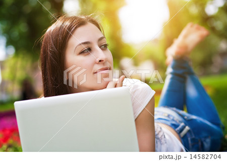 smiling girl laying on grass with laptop smiling girl laying on grass with laptop 14582704