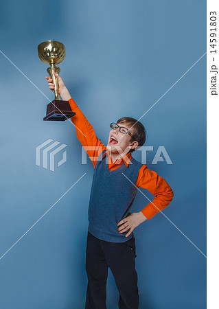 European-looking boy of ten years in glasses holding a cup award on a blue background European-looking boy of ten years in glasses holding a cup award on a blue background 14591803