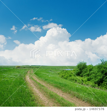 dirty road in green landscape and clouds over it dirty road in green landscape and clouds over it 14697376