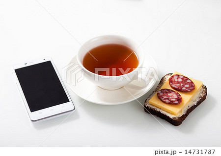 White smartphone,  a cup of tea and sandwich  White smartphone,  a cup of tea and sandwich  14731787