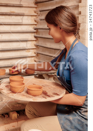 Woman puts clay pots on the shelf 14743723