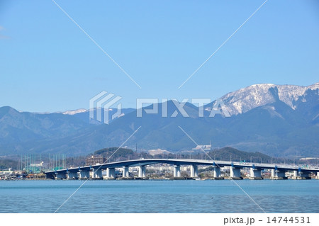 早春の琵琶湖を通る琵琶湖大橋と背景になる雪の比良山 14744531
