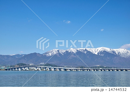 早春の琵琶湖を通る琵琶湖大橋と背景になる雪の比良山 14744532