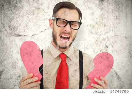 Composite image of geeky hipster crying and holding broken heart 14745799