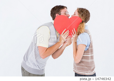 Geeky hipster couple kissing behind heart card 14746342