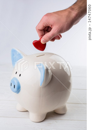 Hand putting heart in piggy bank Hand putting heart in piggy bank 14747060