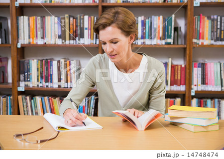 Teacher writing on notepad at library Teacher writing on notepad at library 14748474