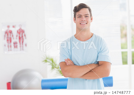 Young man smiling at camera with arms crossed Young man smiling at camera with arms crossed 14748777