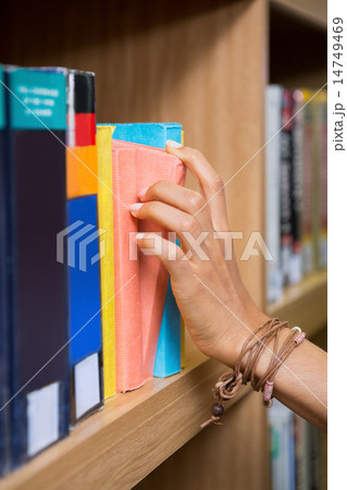 Student picking a book from shelf in library Student picking a book from shelf in library 14749469