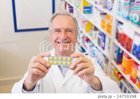 Senior pharmacist holding up blister packs Senior pharmacist holding up blister packs 14750398