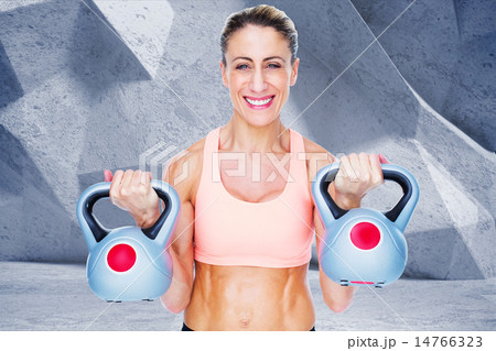 Composite image of smiling female crossfitter lifting kettlebell 14766323
