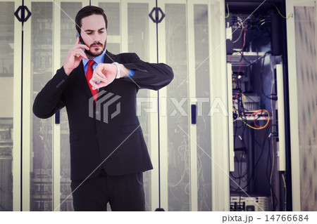 Composite image of serious businessman checking the time while o Composite image of serious businessman checking the time while o 14766684