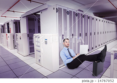 Composite image of businessman sitting on the floor with feet up 14767052