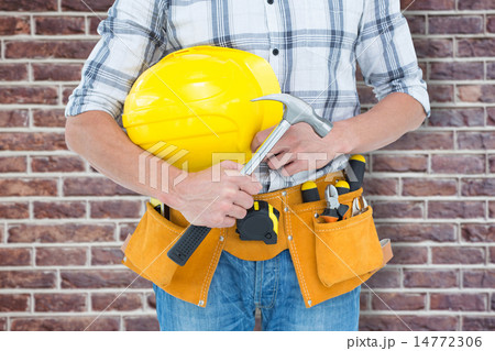 Composite image of technician holding hammer and hard hat Composite image of technician holding hammer and hard hat 14772306