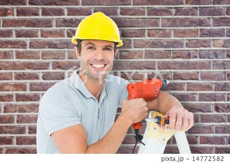 Composite image of happy technician holding drill machine while leaning on ladder Composite image of happy technician holding drill machine while leaning on ladder 14772582