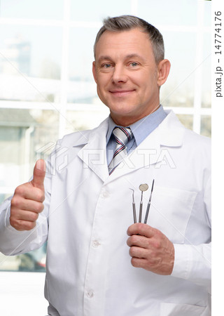 Dentist with tools showing thumb up Dentist with tools showing thumb up 14774176