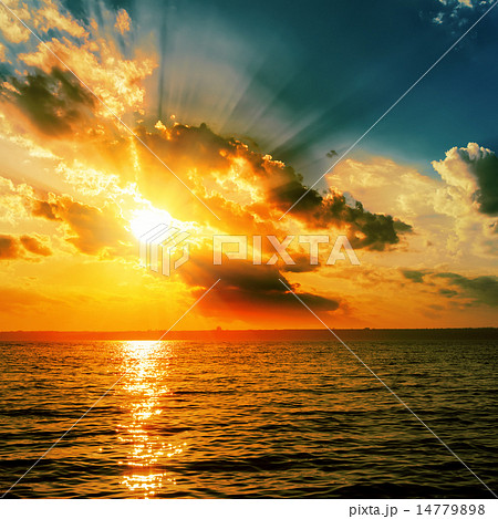 dramatic orange sunset over dark water 14779898