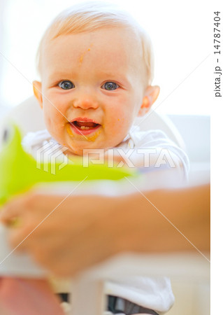 Eat smeared smiling baby girl sitting in baby chair Eat smeared smiling baby girl sitting in baby chair 14787404