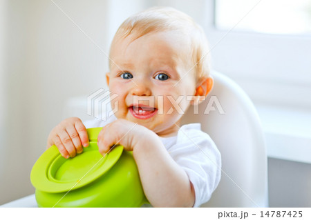 Adorable baby girl sitting in baby chair and playing with plate Adorable baby girl sitting in baby chair and playing with plate 14787425